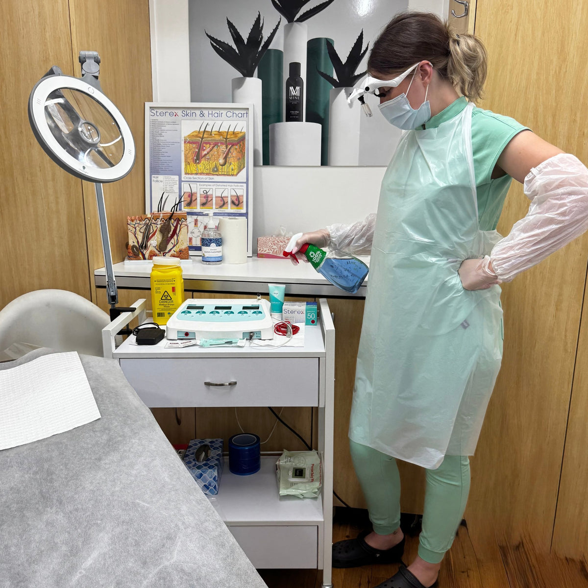 Therapist in PPE disinfecting an electrolysis treatment room - SHBBINF002 infection control training