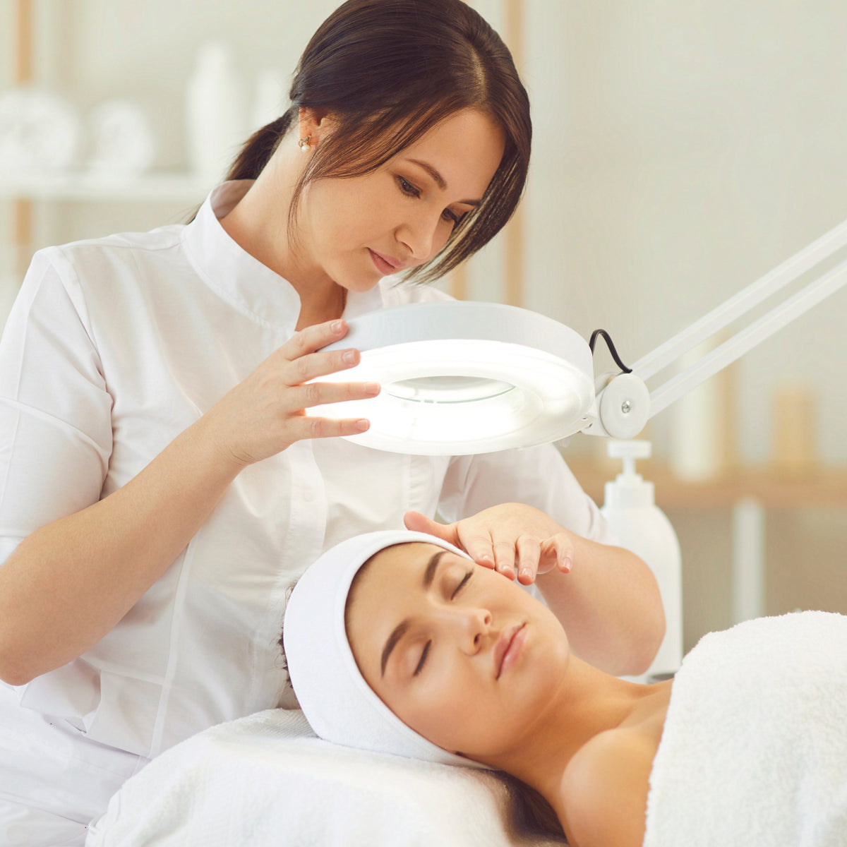Beauty therapist analysing a client's skin under a magnifying lamp - SHBBSSC001 skin structure and functions